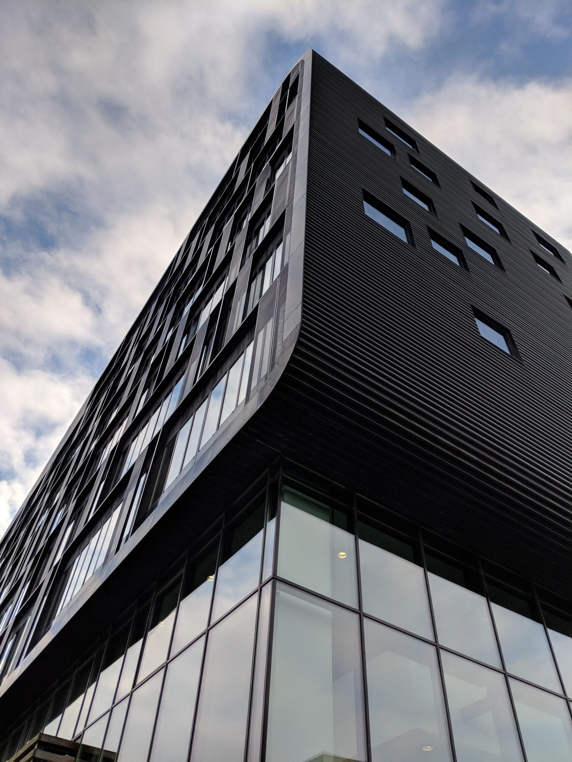 vertical low angle shot high rise black building with glass windows scaled